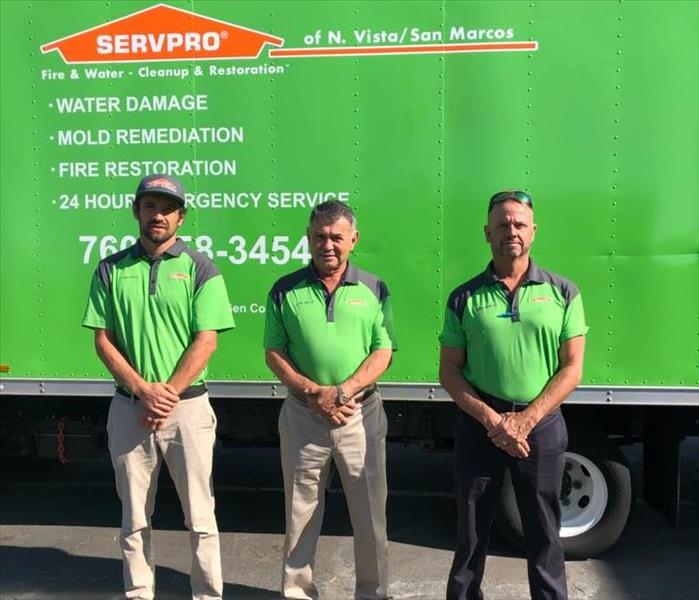 Three owners in green standing in front of SERVPRO truck.